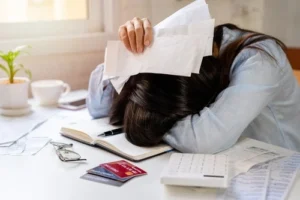 A stressed individual surrounded by credit cards and bills epitomizes the struggle to determine eligibility for Chapter 7 Bankruptcy.