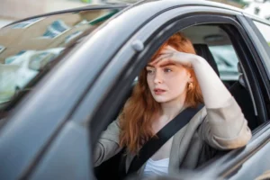 A serious-looking person sits in a car, symbolizing the motor vehicle exemption in Nevada bankruptcy law.